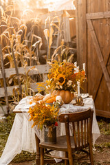 Cozy autumn table decoration for a thanksgiving party outdoors. Centrepiece with sunflowers, candles, pumpkins as decor. Elegant wedding fall arrangement, beautiful setting for a romantic lunch.