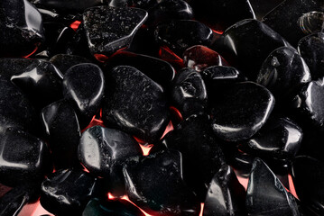 Black polished stones texture background and red light