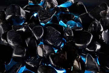Black polished stones texture background and blue light