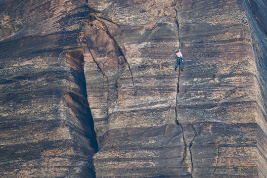 Recreational rock climber, shirtless man with safety helmet, harness, and rope, high up on a steep vertical cliff rock wall, Zion National Park, Utah
 - Powered by Adobe
