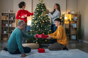 Family celebrating christmas, decorating tree and exchanging gifts