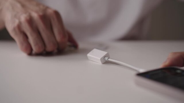 Male hands connecting OTG cable to smartphone, enabling data transfer, device charging and peripheral connection, showcasing mobile connectivity and technology integration. Shooting in slow motion.