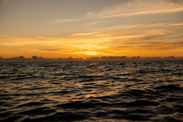 Golden sunrise in Itacaré, Bahia, Brazil. Boats floating on calm sea, yellow light on the horizon, tropical coastal landscape with warm tones and natural beauty.