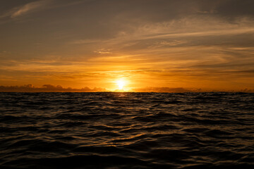 Golden sunrise in Itacaré, Bahia, Brazil. Boats floating on calm sea, yellow light on the horizon, tropical coastal landscape with warm tones and natural beauty.