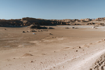 Moon Valley, Atacama Desert, Chile – September 11th, 2025 – Wide desert view with a solitary white vehicle crossing the arid plain, framed by rugged sandstone formations and vast open sky.