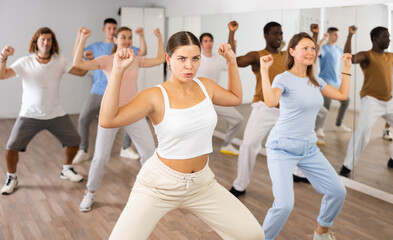 Group of energetic different people learning dance at dance class