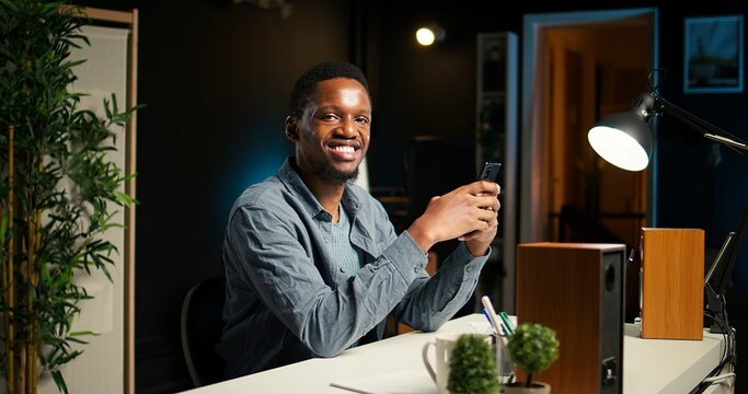 Independent adult teleworking from home and using his mobile phone, navigating social media and answering emails before starting his daily tasks completion. Comfortable modern setup. Camera A.