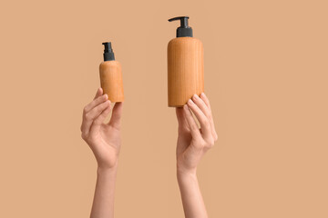 Female hands with bottles of cosmetic products on brown background