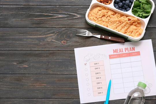 Healthy products and weekly meal plan on wooden background. Diet concept