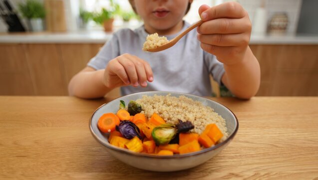 Young child learning and enjoying a healthy, wholesome meal of quinoa and roasted vegetables, promoting nutritious eating habits for growth and wellbeing