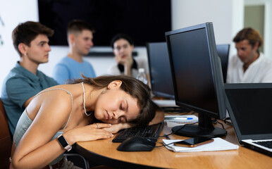 Fototapeta premium Exhausted students find solace in sleep, their heads resting on lecture hall desks during break.