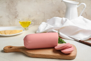 Board with slices of tasty boiled sausage, cheese and rosemary on grunge white background