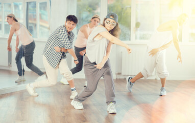 Stylishly dressed young people learn to dance hip-hop and breakdance in a dance studio
