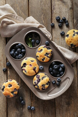 Napkin and baking tray with tasty blueberry muffins on wooden background
