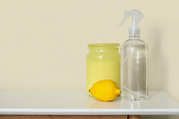 Bottle of aroma spray with lemon and jar on shelf in room, closeup