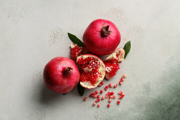 Fresh ripe pomegranates with seeds and leaves on grunge background © Pixel-Shot