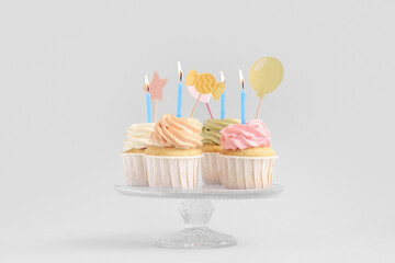 Sweet Birthday cupcakes with burning candles on grey background