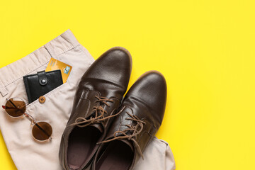 Stylish men's accessories with shoes and trousers on yellow background