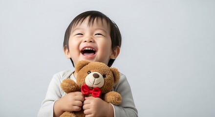 Adorable toddler boy with a teddy bear isolated on a plain background pure joy laughter