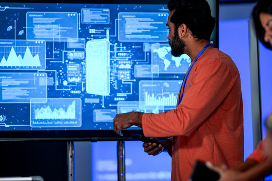 data scientist presents a new business intelligence BI dashboard. He is explaining the key performance indicators KPI and complex data visualizations to stakeholders. computer screen show model phone. - Powered by Adobe