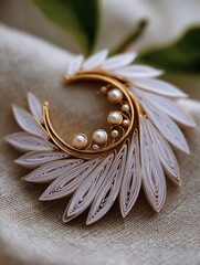 Delicate, crescent-shaped brooch, crafted from layers of delicate paper and adorned with lustrous pearls, features a golden wire frame and creates an elegant, ethereal design.