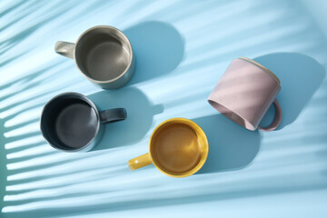 Set of stylish ceramic mugs with shadows on color background