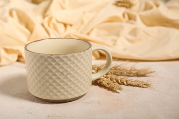 Ceramic mug with ears of wheat on light table