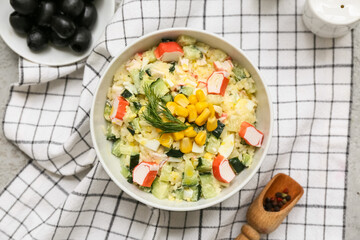 Bowl of salad with crab sticks, corn and cucumber on napkin