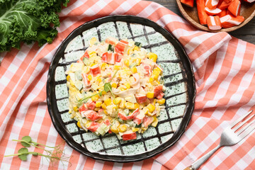 Plate of salad with crab sticks, corn and cucumber on napkin