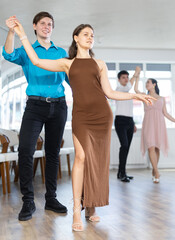 Young man and young woman dance ballroom dance waltz in studio