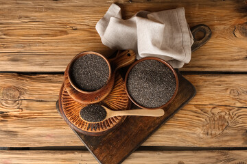 Bowls and spoon with chia seeds on wooden background