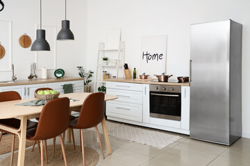 Interior of kitchen with dining table, white counters and shelf unit