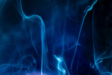 Colorful blue smoke swirls in the dark creating a mystical atmosphere and depth
