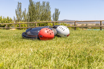 Electric unicycle with helmets lie on the green lawn against a wooden fence