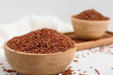 Tray with bowls of raw brown rice on white background