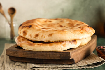 Wooden tray with tasty lavash on green grunge table
