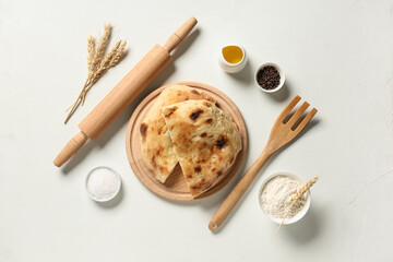 Wooden board with pieces of tasty lavash, rolling pin, fork and ingredients on white background