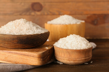 Bowels of raw rice and board on table against wooden background. Closeup