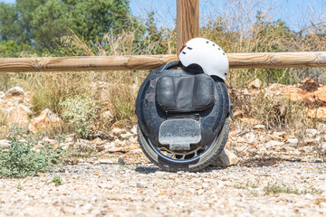 Black Electric unicycle with a white helmet leaning against wooden fence
