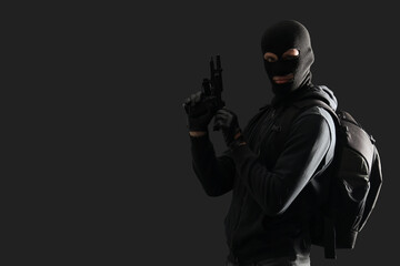 Male thief with gun on black background