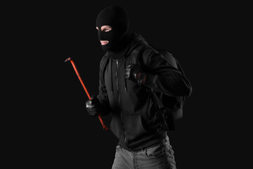 Male thief with crowbar on black background