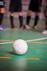 Indoor futsal game with ball in foreground