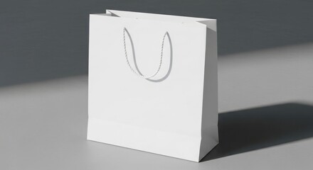 Blank white paper shopping bag with handles, sitting on a gray surface.
