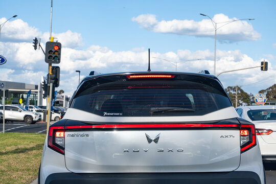 Rear view of a Mahindra SUV at a traffic light on a suburban road in Australia, featuring the Mahindra logo and branding on the back of the vehicle.