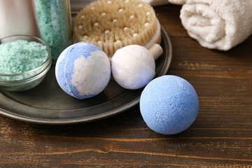 Composition with tray, bath bombs and bowl of sea salt on brown wooden background, closeup