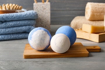 Composition with cutting board and bath bombs on grey wooden background, closeup