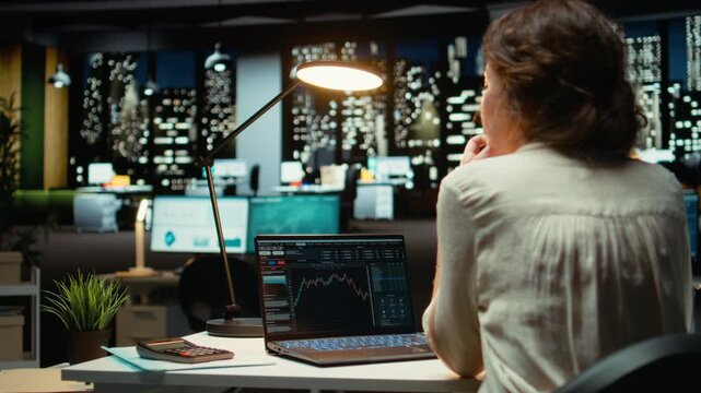 Employee monitors live stock market trends and cryptocurrency exchanges, leveraging technology and professional analysis to achieve trading objectives and optimize revenue. Night time. Camera A.