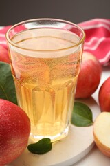 Fresh cider in glass and apples on table, closeup