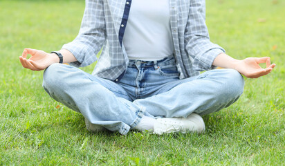 Young woman meditating on grass outdoors. Zen concept