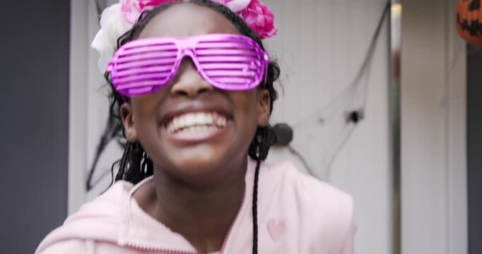 African American girl reaching out with bucket on Halloween porch twirling wand for trick-or-treat - Powered by Adobe